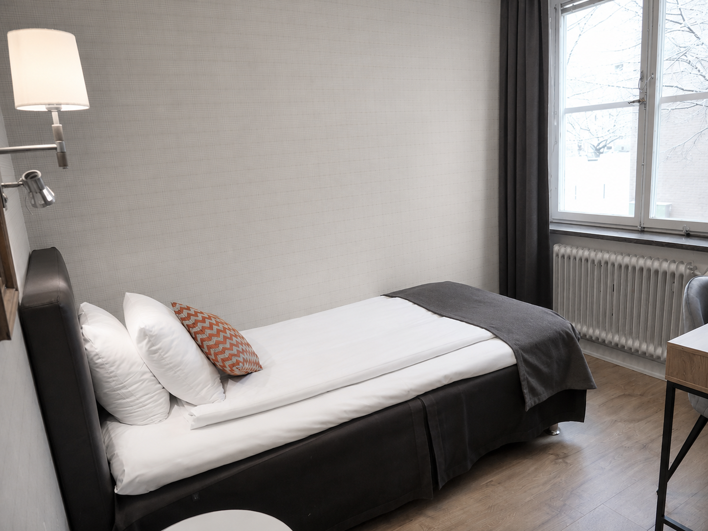 Bright hotel room at Hotel Arkad in Västerås with a single bed, window and stylish interior.