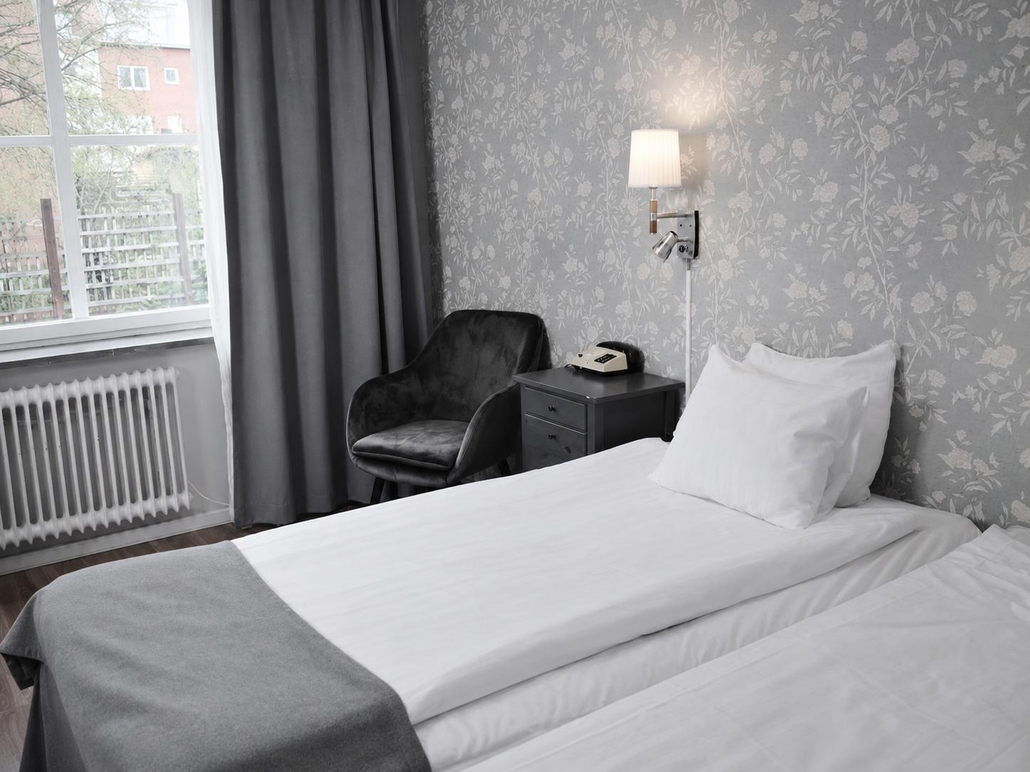 Economy double room at Hotel Arkad in Västerås with a bed, armchair, window and modern interior.