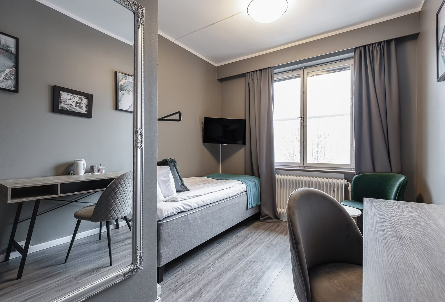 Ljust Enkelrum Standard på Hotel Arkad i Västerås med enkelsäng, skrivbord, TV och fönster.